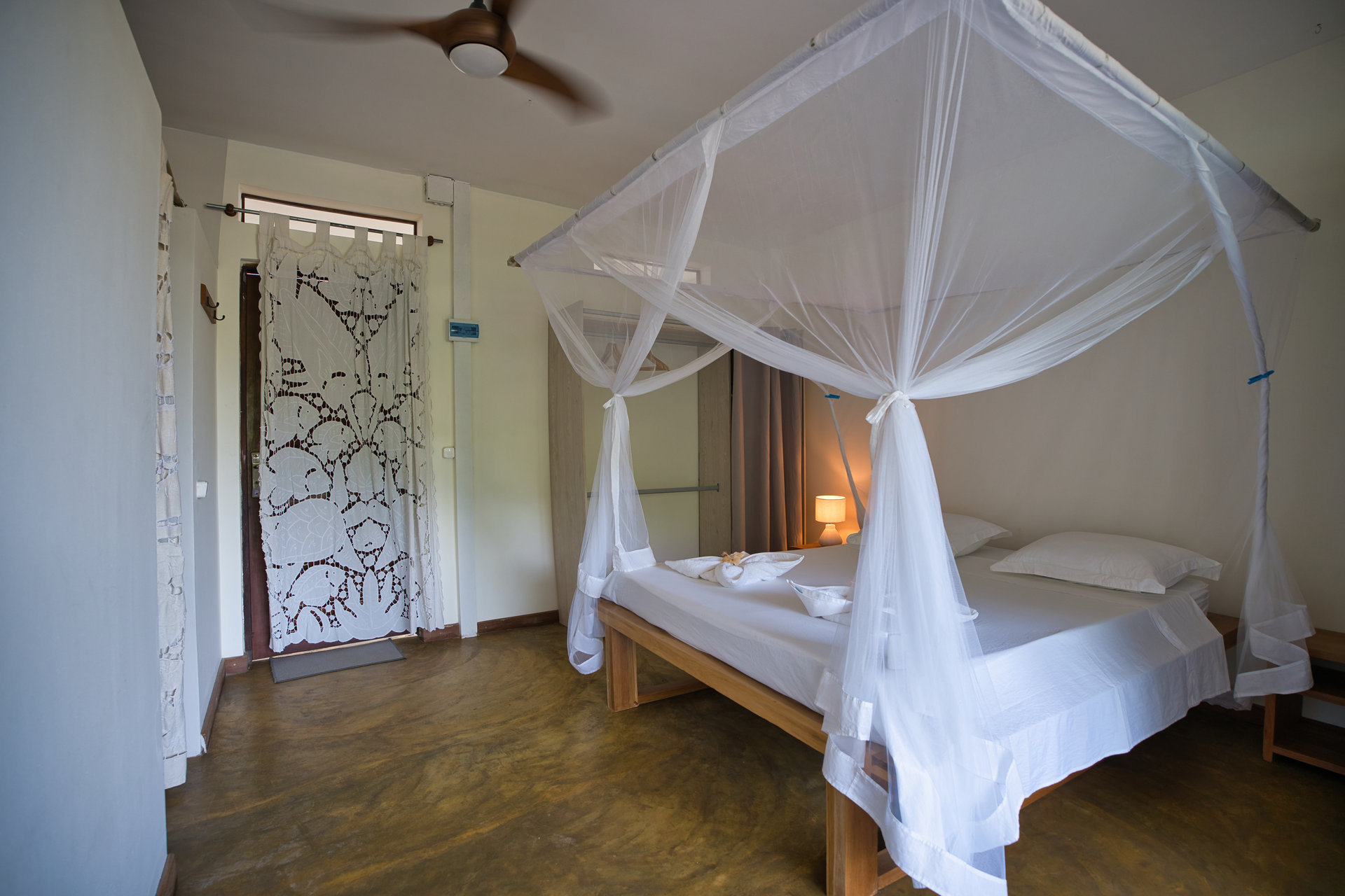 Ocean View Studio — canopy bed with ceiling fan and lace curtain